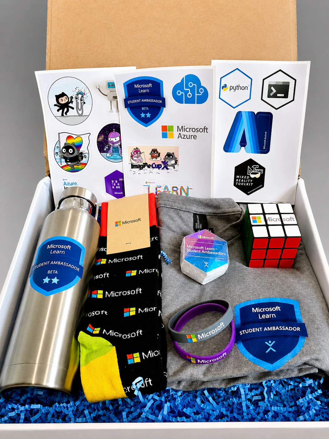 Kit de brindes do antigo marco Beta Student Ambassador com garrafa, camiseta, meias, adesivos e cubo mágico